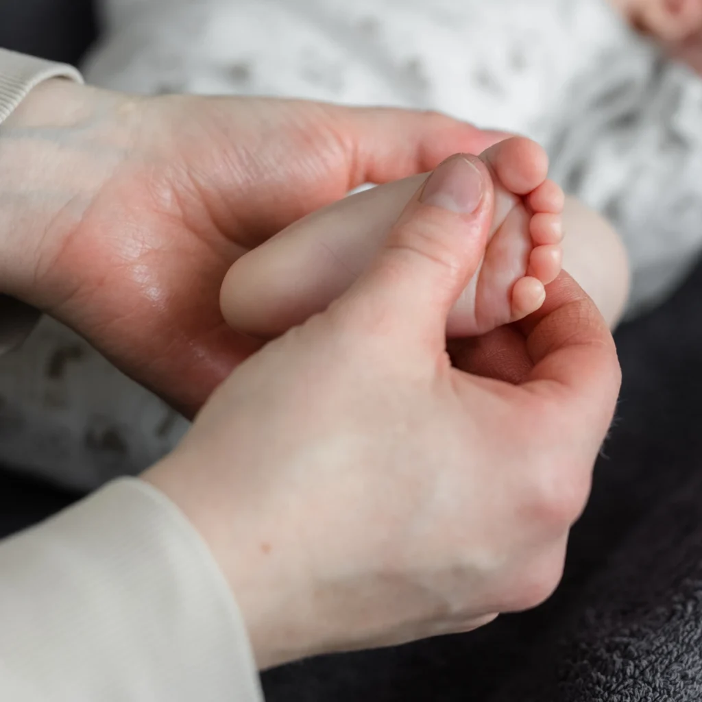 Vauvahieroja hieroo lempeästi pienen vauvan jalkapohjaa.